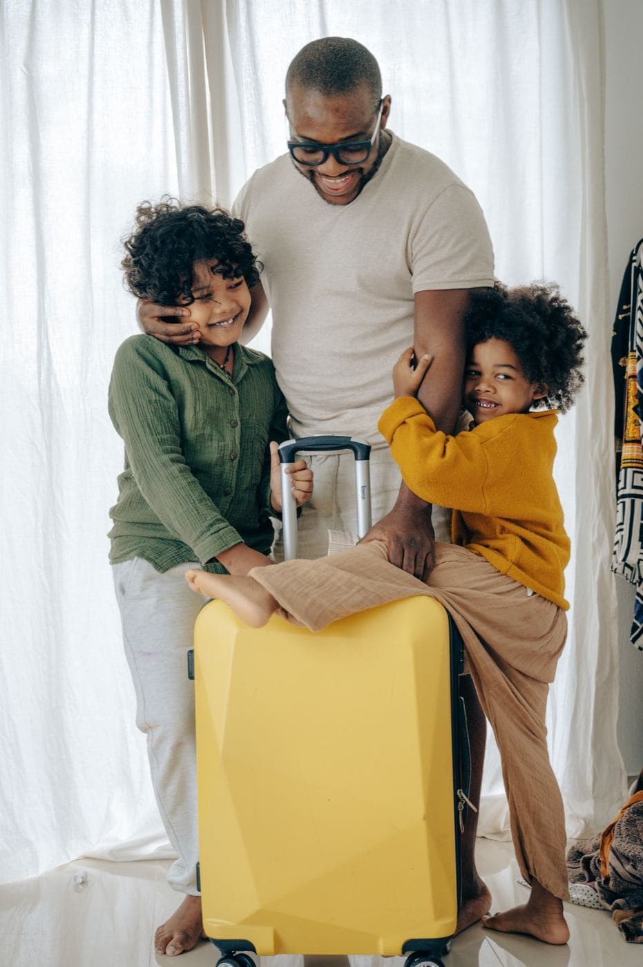 Un père et ses deux enfants avec une valise