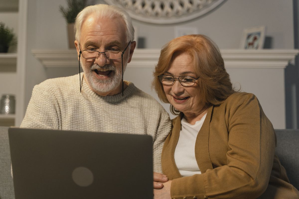 Un couple aîné joyeux en consultation vidéo sur leur portable